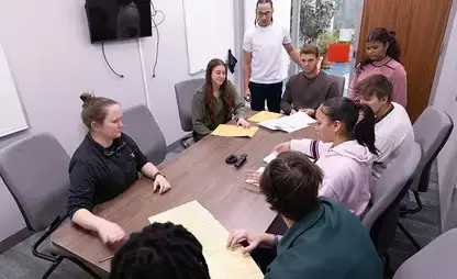 Participants of the VITA program sit around a conference table discussing taxes.