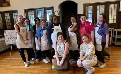 Diverse group of students wearing aprons posing for a group photo.
