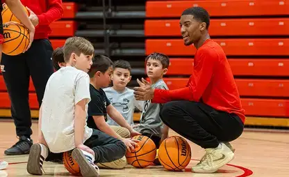 A group of five boys pretend to listen to a basketball coach during Kids in Sports Day.