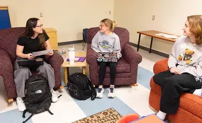 Three students sit and discuss a class topic during Psychology class.