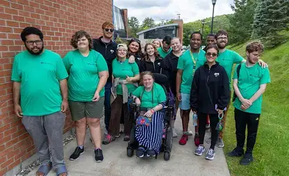 A diverse group of participants of the Springbrook program pose together during Pass Through the Pillars.