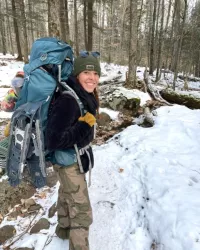 A woman smiling at the camera during a winter hike.