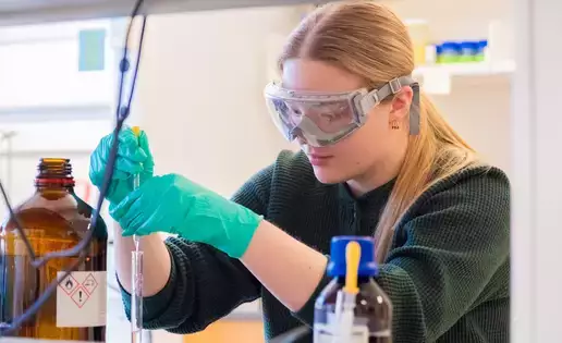 A female biochemistry student in the lab mixing chemicals