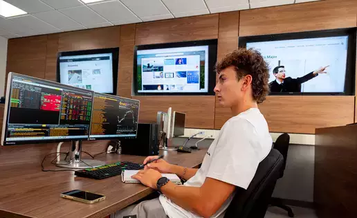 An economics student reviews the Bloomberg terminals in class