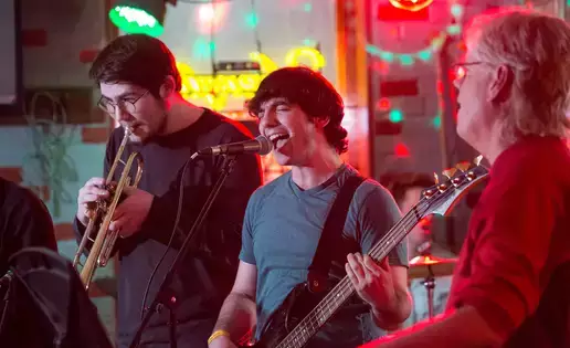 An electric bass player sings intensely into a microphone