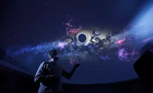 Josh Nollenberg stands underneath the digital planetarium ceiling