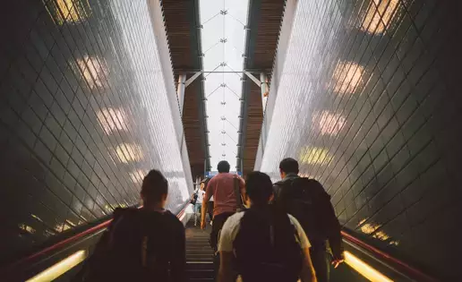 Individuals walk up a large staircase in a modern rail station