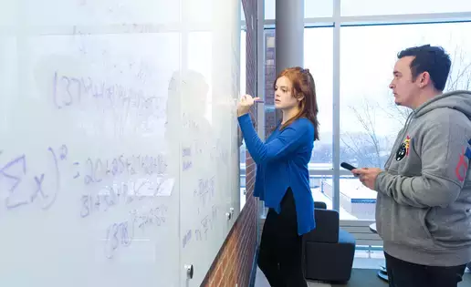 Students review statistical analysis calculations on a large whiteboard