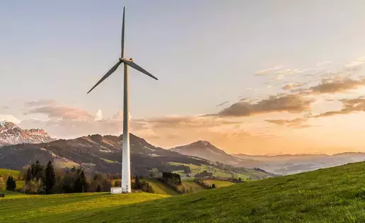 An enormous wind turbine stands tall over a majestic landscape