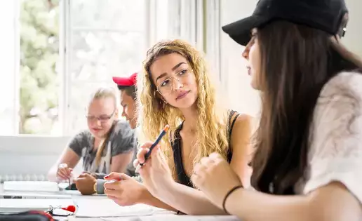 Group of students engaged in a lively discussion in a bright classroom setting.