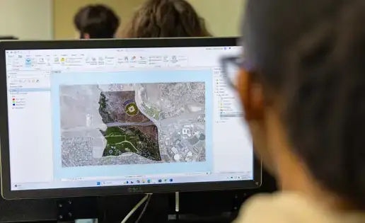 GIS student reviews map data on screen.
