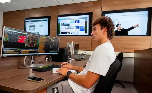 Finance student sits at a Bloomberg terminal during class lecture.