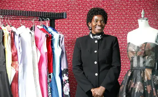 Annacleta Chiweshe stands between a rack of dresses and a dress form