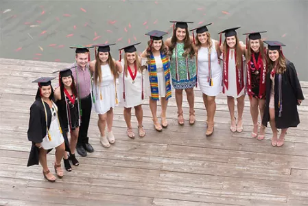 Graduating students standing on the dock next to Hunt Union pond.