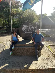 Faculty and student posing in front of a sign for Victoria Falls.