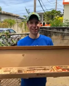 Sean Robinson holding a large box of pizza.