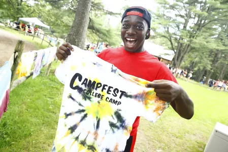 Man holding up a tye-die shirt that says CampFest on it.