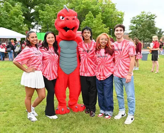 Group of 5 students wearing red and white tie-dye shirts posing with Red at a opening picnic