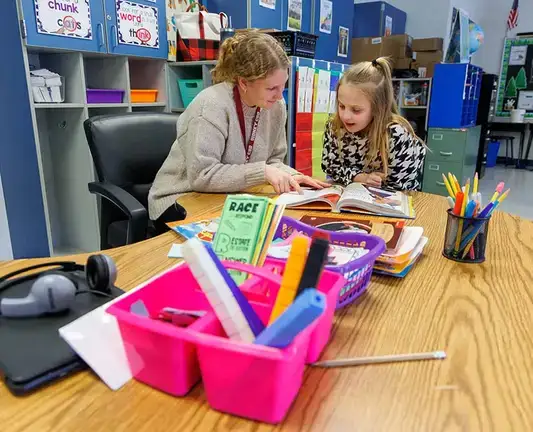 Student teacher helps a child with reading.