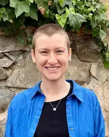 Kimmy Cushman, SUNY Oneonta alumna and PhD, in a blue shirt, smiling.