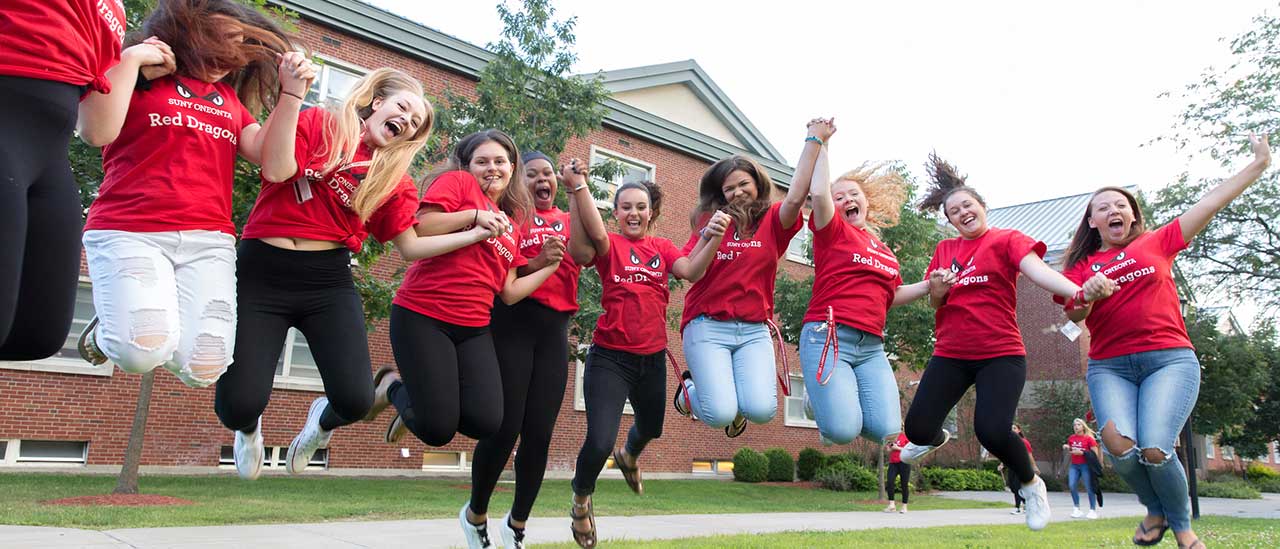 Students jump in the air in front of Wilber Hall